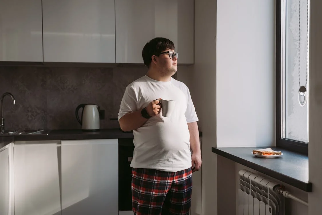 An image of an adult with a developmental disability having coffee in his apartment